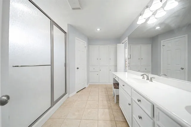 a spacious bathroom with a double vanity sink a large mirror and shower