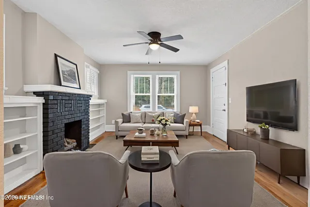 a view of an empty room with wooden floor fireplace and a window