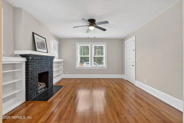 a living room with wooden floor and a fireplace