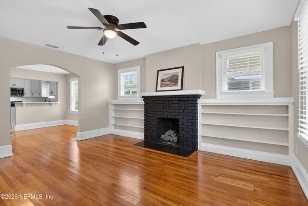 a view of empty room with wooden floor and fan