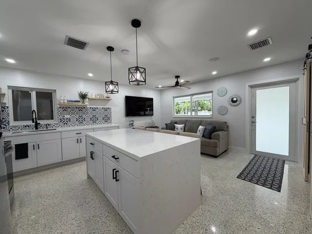 a large white kitchen with a stove a sink a refrigerator and a fireplace