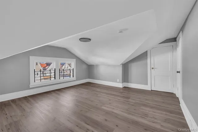 a view of an empty room with wooden floor and a painting on the wall