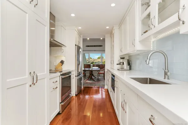 a kitchen with white cabinets appliances and wooden floor