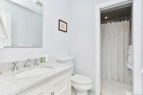 a bathroom with a granite countertop sink mirror vanity and toilet