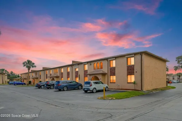 a front view of a building with parking space and a car parked in it