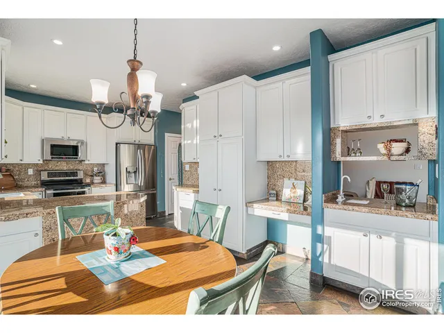 a kitchen with stainless steel appliances kitchen island granite countertop a refrigerator a stove a sink dishwasher and white cabinets with wooden floor