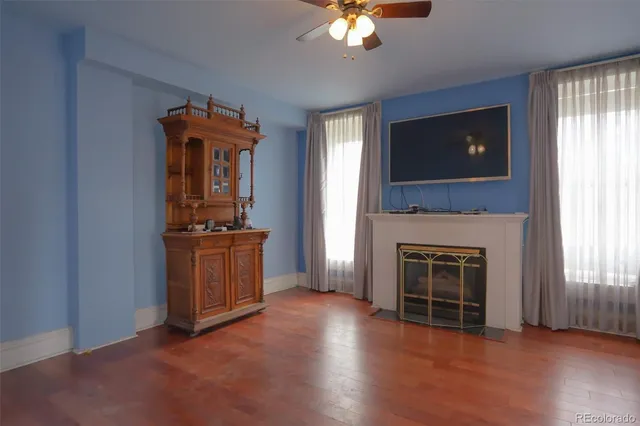 an empty room with windows fireplace and wooden floor