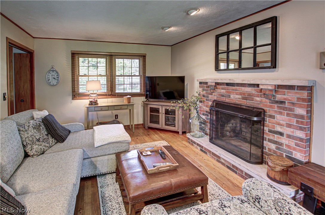 910 Andrews Road Medina, OH 44256 - Photo 18 of 45 Family room with light hardwood / wood-style floors, ornamental molding, and a brick fireplace