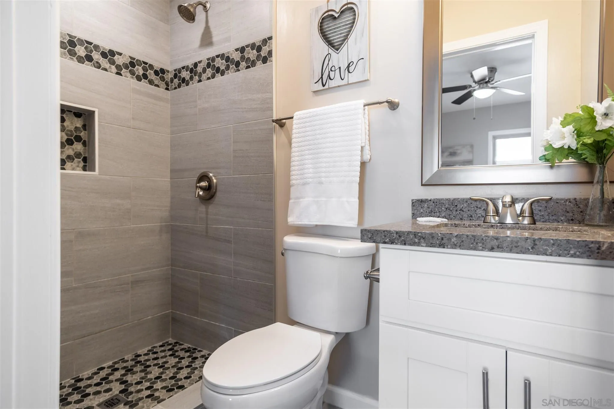 7204 Waite Drive La Mesa, CA 91941 - Photo 5 of 18 a bathroom with a granite countertop sink a toilet a mirror and shower