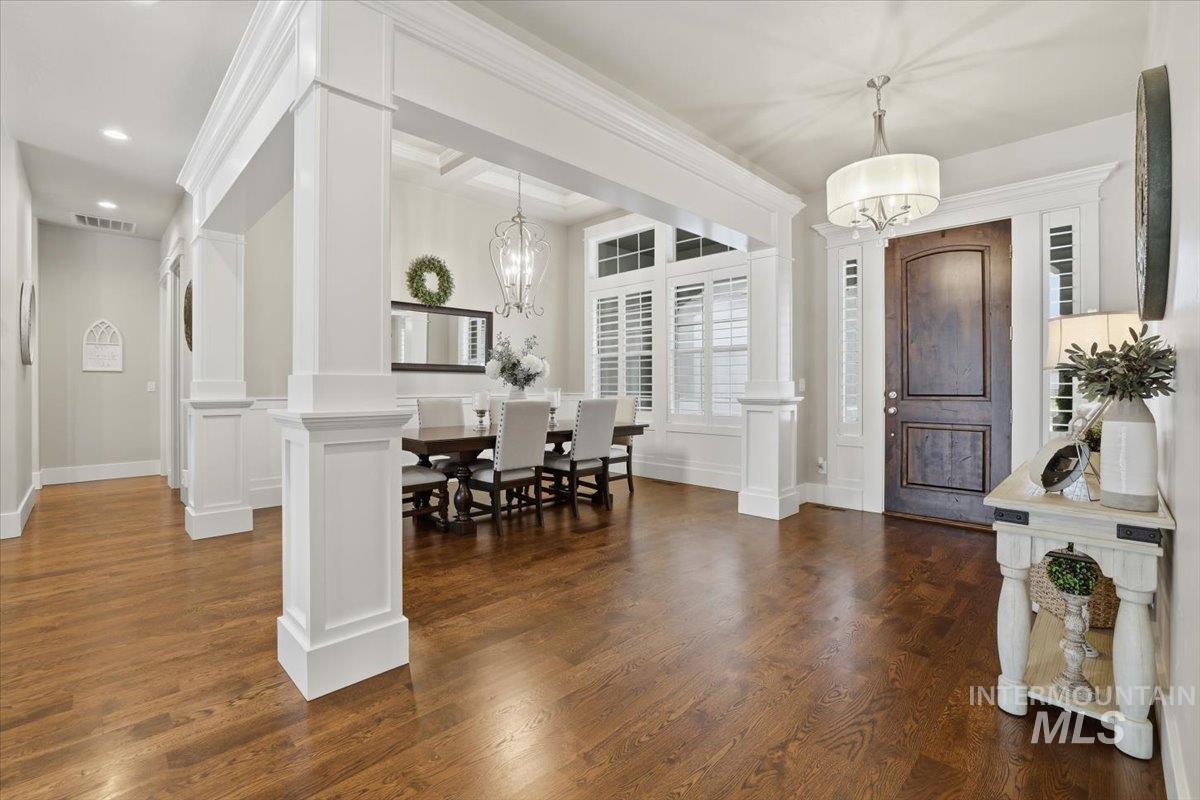 6590 North Fairborn Avenue Meridian, ID 83646 - Photo 11 of 49 Entryway with dark wood finished floors, ornamental molding, a decorative wall, a chandelier, and decorative columns