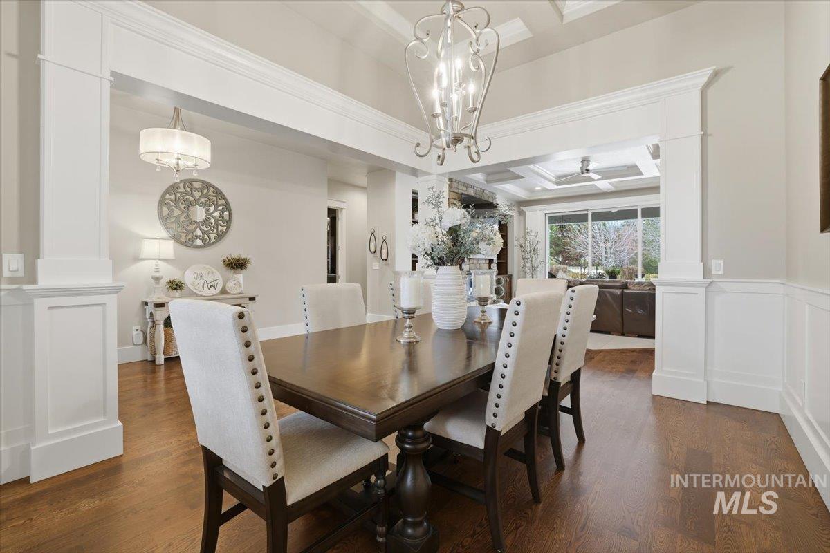 6590 North Fairborn Avenue Meridian, ID 83646 - Photo 12 of 49 Dining area with coffered ceiling, ornate columns, a decorative wall, dark wood-style floors, and beam ceiling
