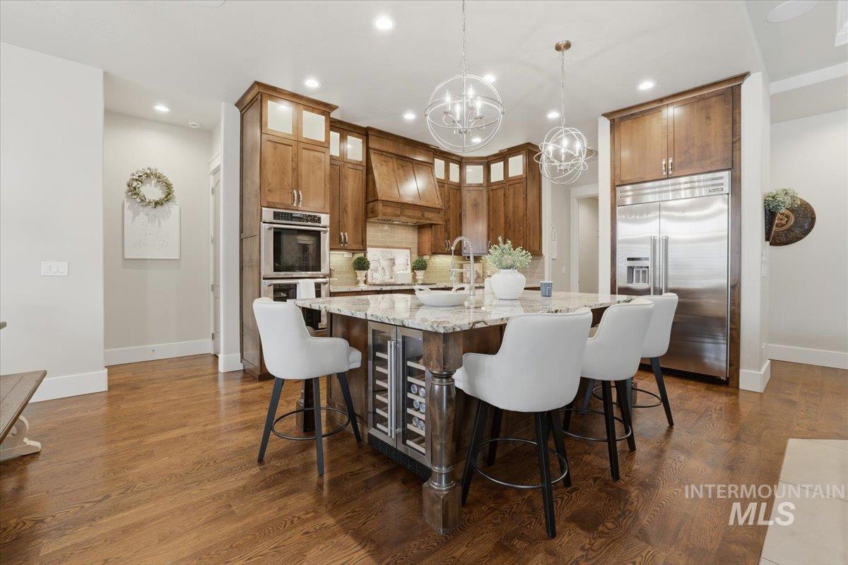 6590 North Fairborn Avenue Meridian, ID 83646 - Photo 21 of 49 Kitchen with light stone countertops, a kitchen bar, a center island with sink, stainless steel appliances, and decorative light fixtures