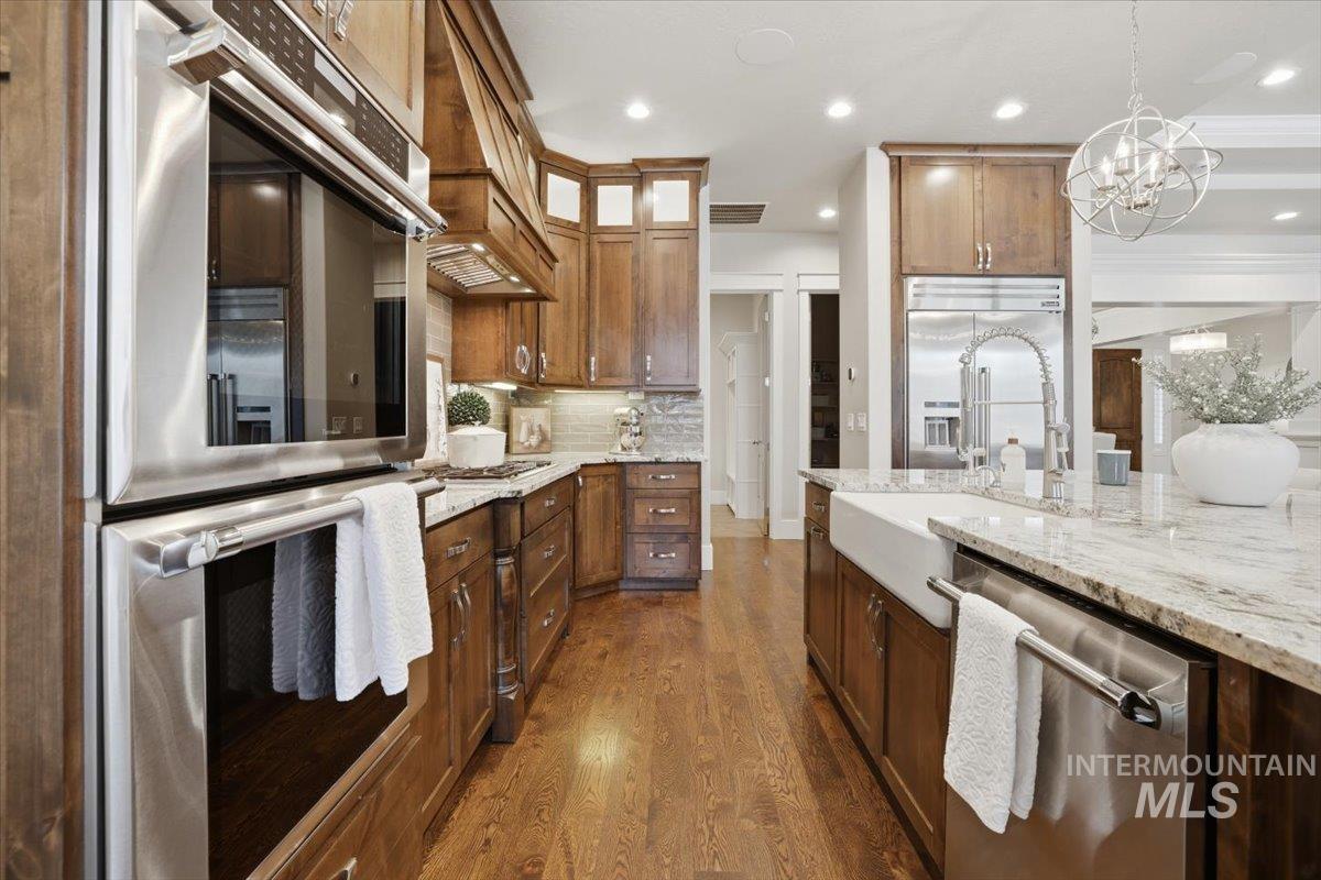 6590 North Fairborn Avenue Meridian, ID 83646 - Photo 22 of 49 Kitchen featuring stainless steel appliances, dark wood-type flooring, recessed lighting, hanging light fixtures, and brown cabinetry