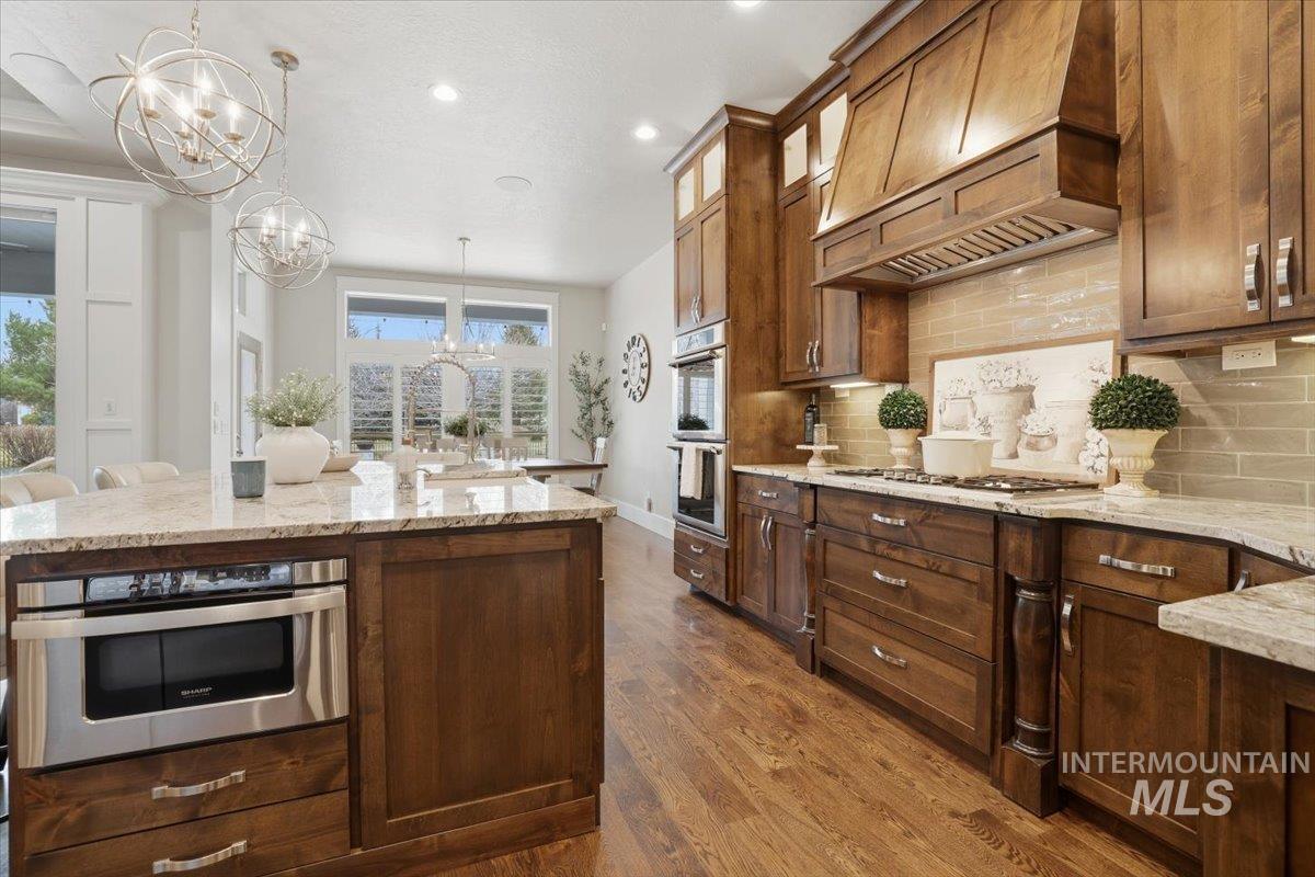 6590 North Fairborn Avenue Meridian, ID 83646 - Photo 23 of 49 Kitchen featuring decorative light fixtures, premium range hood, light stone counters, recessed lighting, and dark wood-style floors