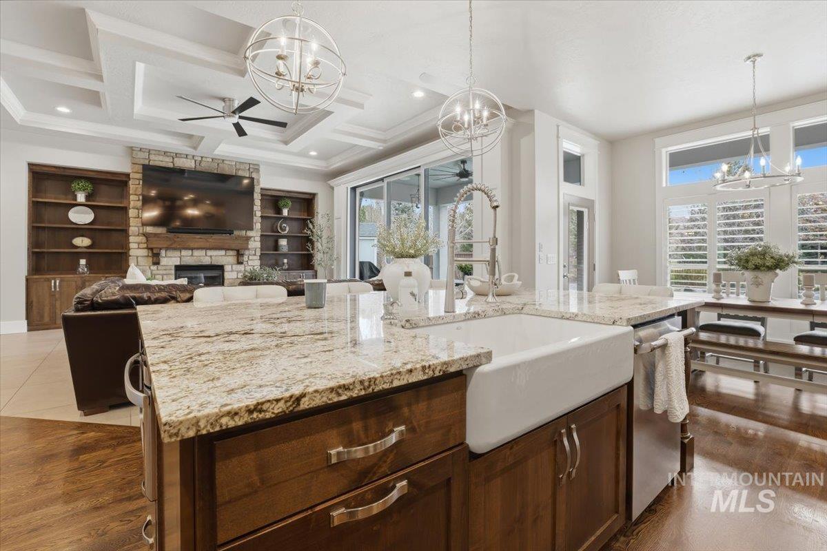 6590 North Fairborn Avenue Meridian, ID 83646 - Photo 24 of 49 Kitchen featuring dark brown cabinetry, a chandelier, a fireplace, hanging light fixtures, and coffered ceiling