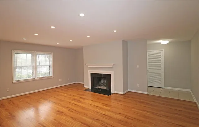 an empty room with wooden floor fireplace and windows