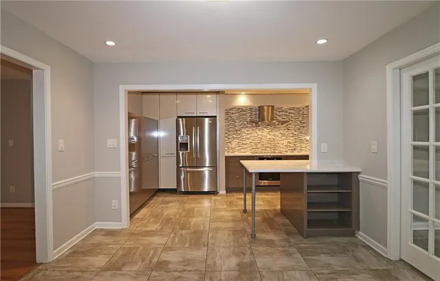 a kitchen with stainless steel appliances kitchen island granite countertop a refrigerator and a sink