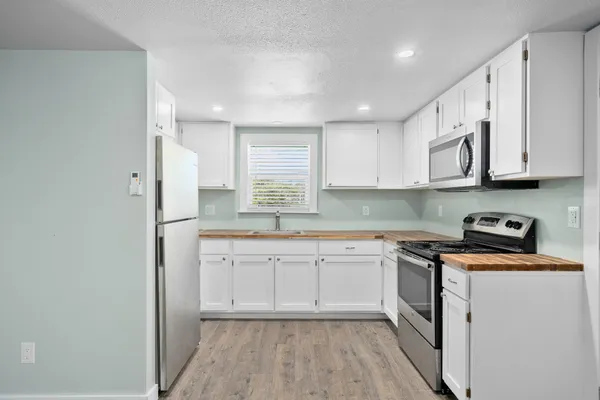 a kitchen with stainless steel appliances granite countertop a stove a sink and white cabinets