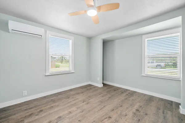 a view of an empty room with a window and wooden floor