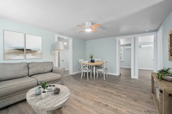 a living room with furniture and a dining table with wooden floor