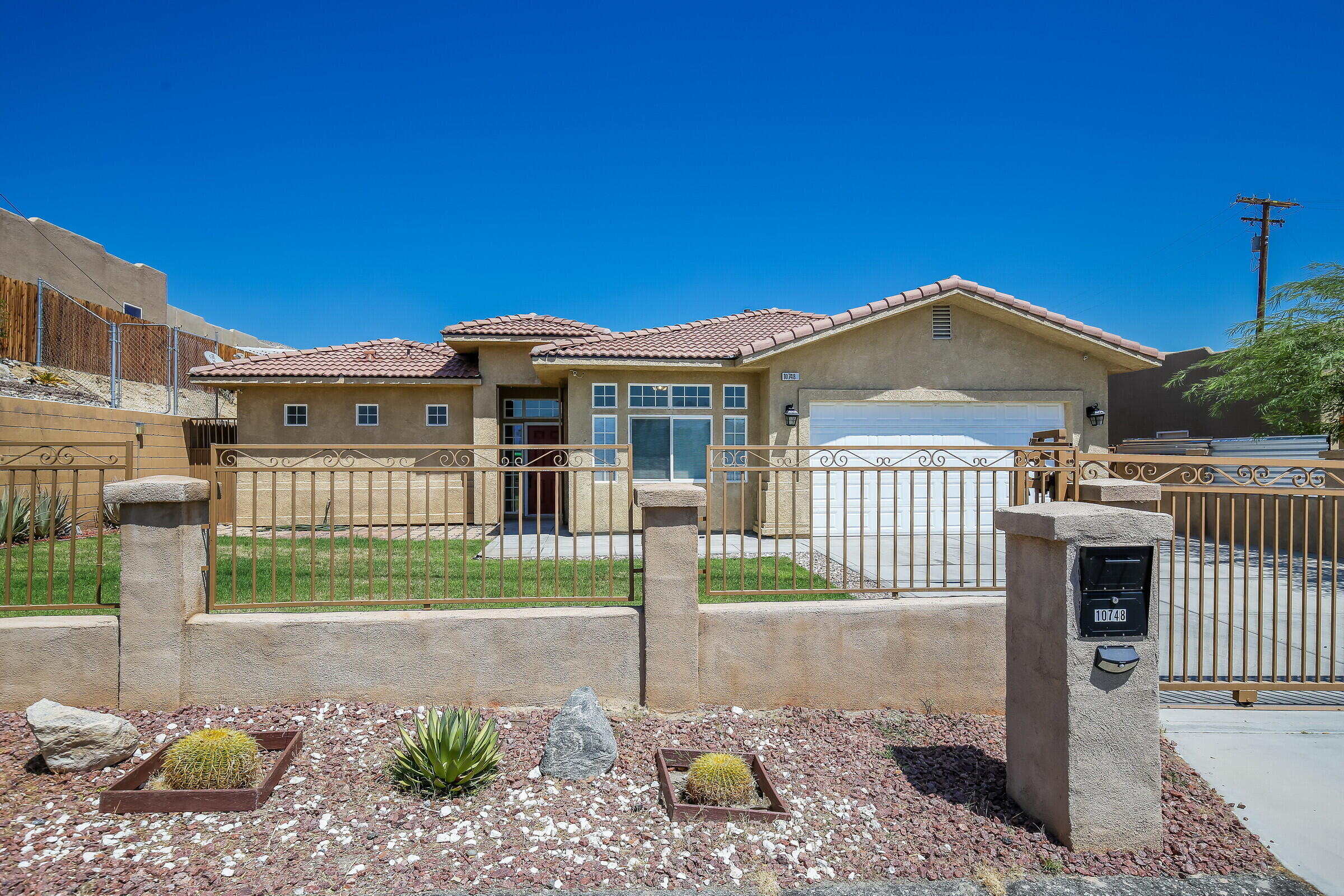10748 Ocotillo Road Desert Hot Springs, CA 92240 - Photo 1 of 28 a front view of a house with a garden