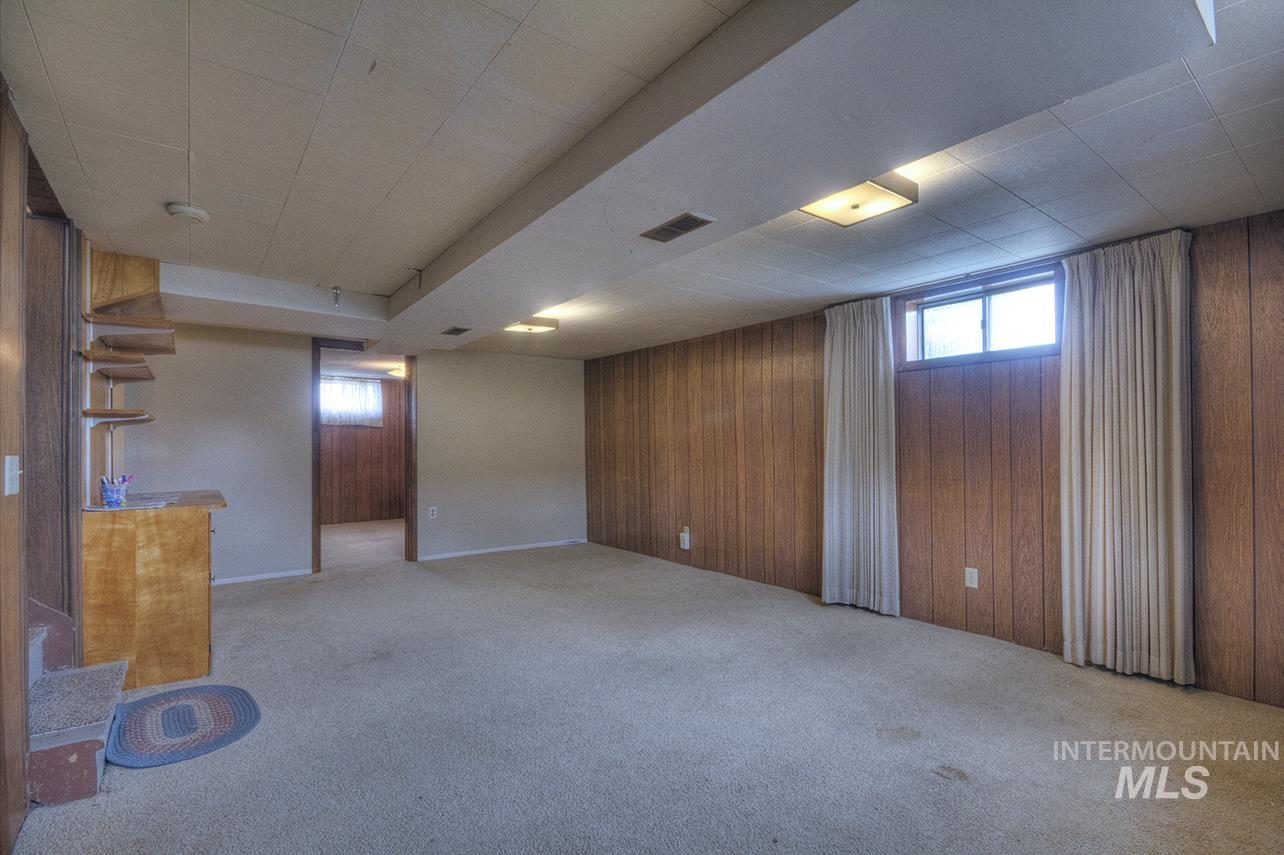 351 West Main Street South Vale, OR 97918 - Photo 10 of 33 Carpeted open-concept room featuring wood-panel accent walls, recessed lighting, a built-in wood-finish bar, and a visible staircase