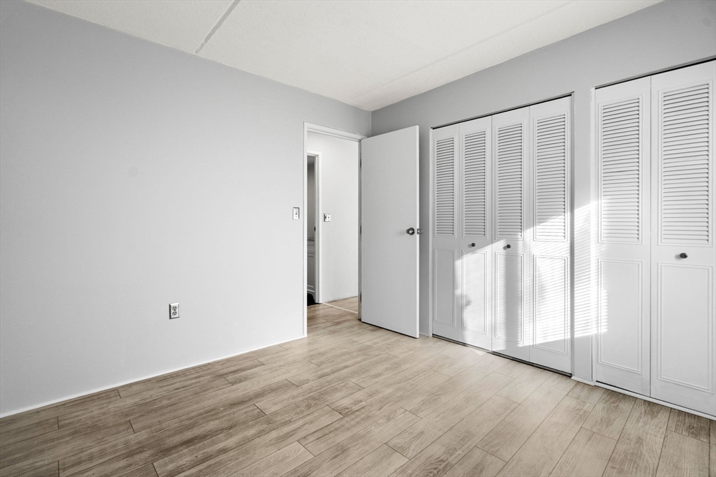 159 Franklin Street, Unit E6 Stoneham, MA 02180 - Photo 17 of 22 an empty room with wooden floor and a window