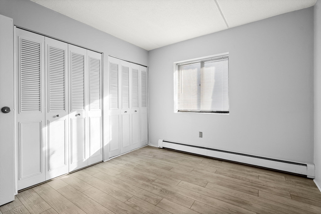 159 Franklin Street, Unit E6 Stoneham, MA 02180 - Photo 18 of 22 an empty room with wooden floor and windows