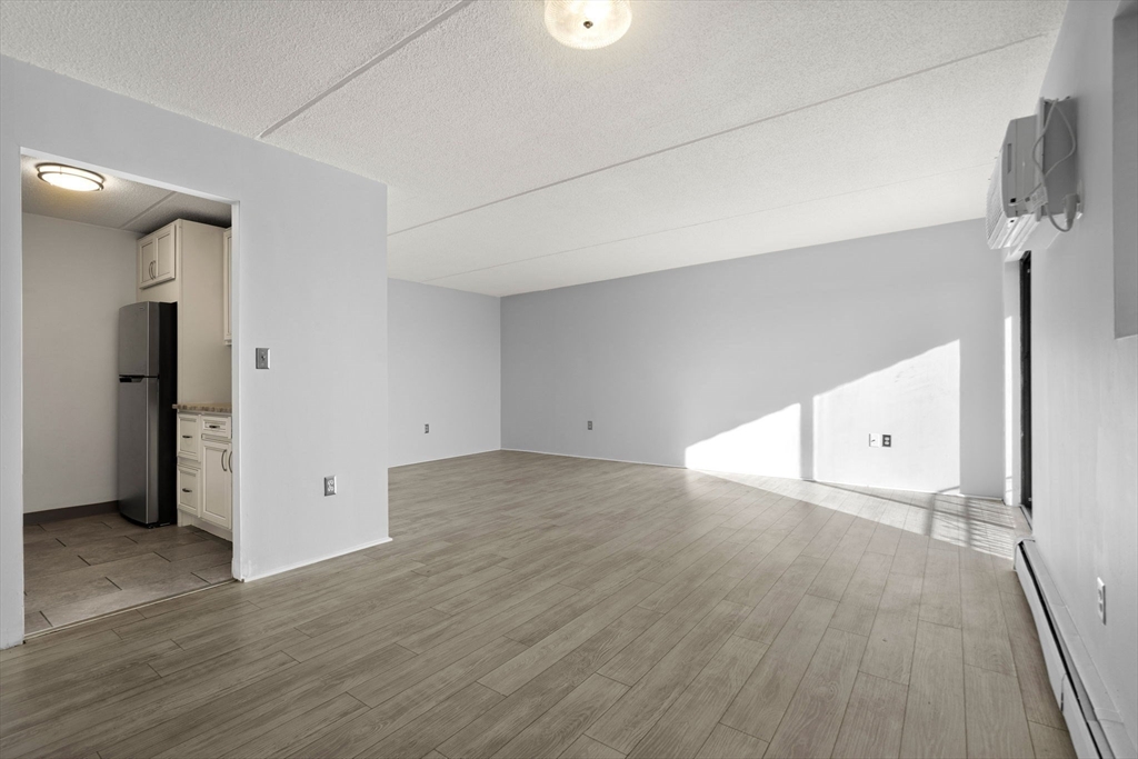 159 Franklin Street, Unit E6 Stoneham, MA 02180 - Photo 7 of 22 an empty room with wooden floor and windows