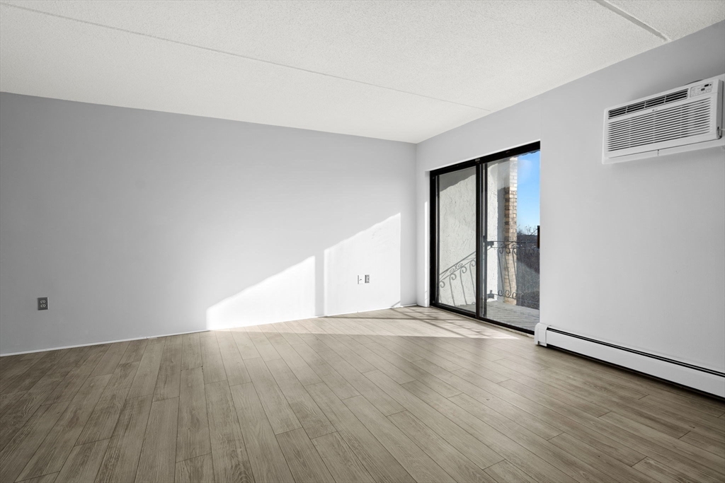 159 Franklin Street, Unit E6 Stoneham, MA 02180 - Photo 9 of 22 an empty room with wooden floor and windows