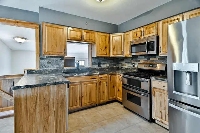 a kitchen with stainless steel appliances granite countertop a stove a sink and a microwave