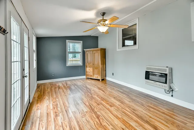 a view of an empty room with window and wooden floor