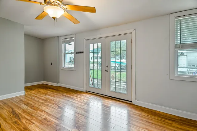a view of an empty room with window and wooden floor