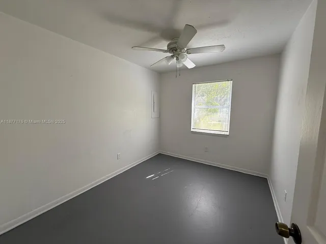 an empty room with a ceiling fan and a window