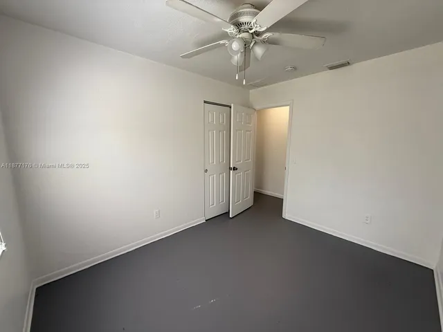 an empty room with windows and ceiling fan