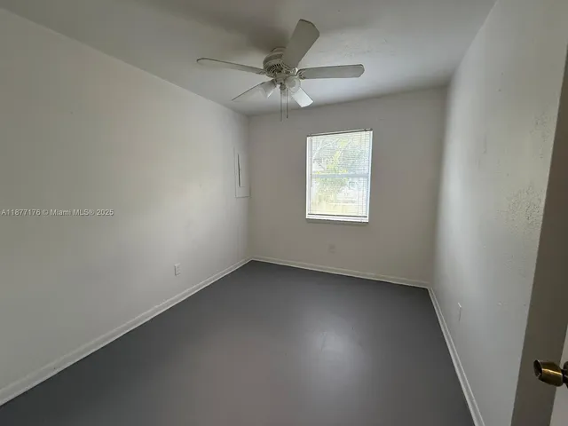 an empty room with a ceiling fan and a window