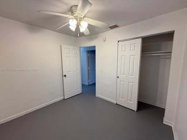 an empty room with a window and a fan