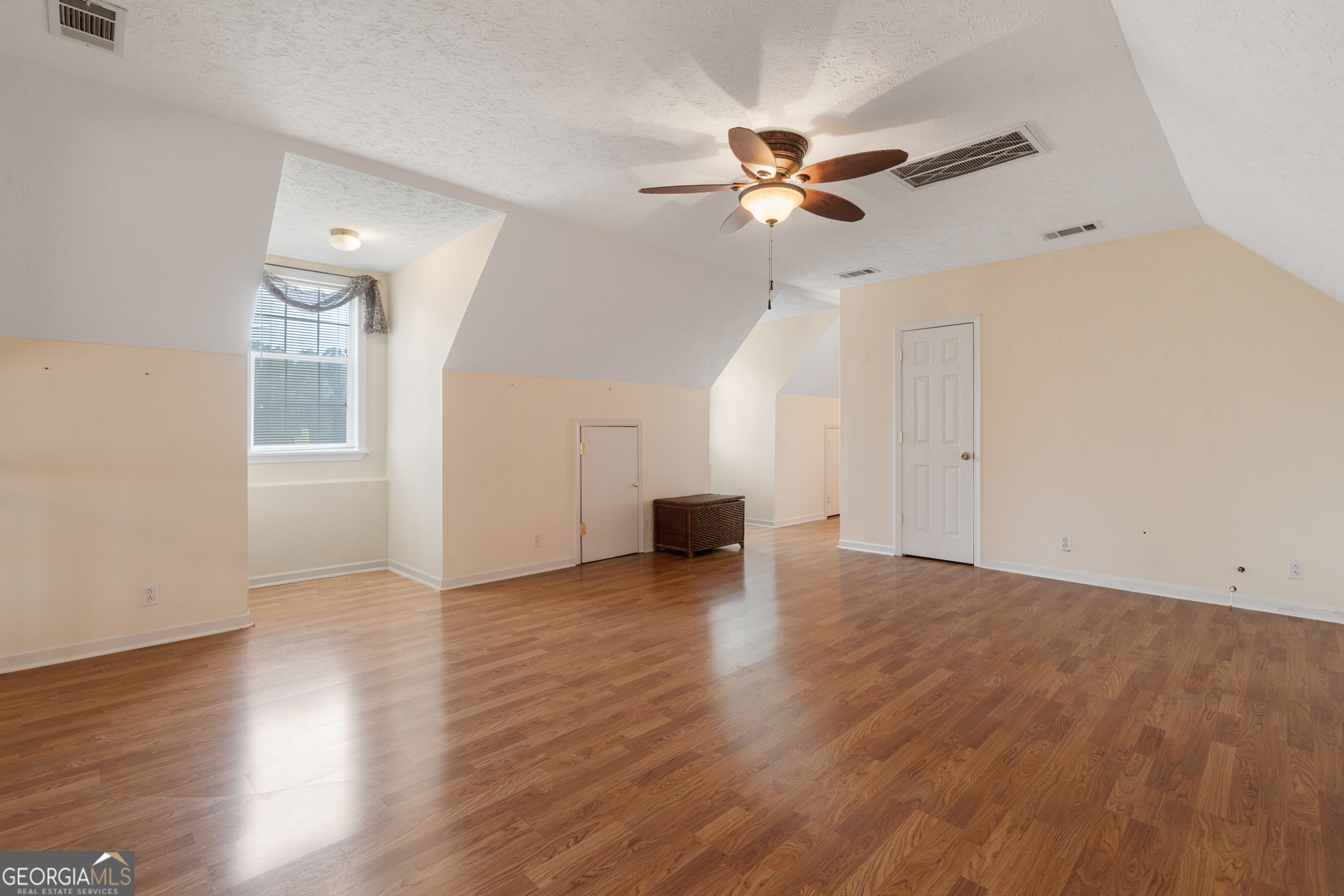 621 Highway 22 Sparta, GA 31087 - Photo 32 of 42 an empty room with wooden floor chandelier fan and windows