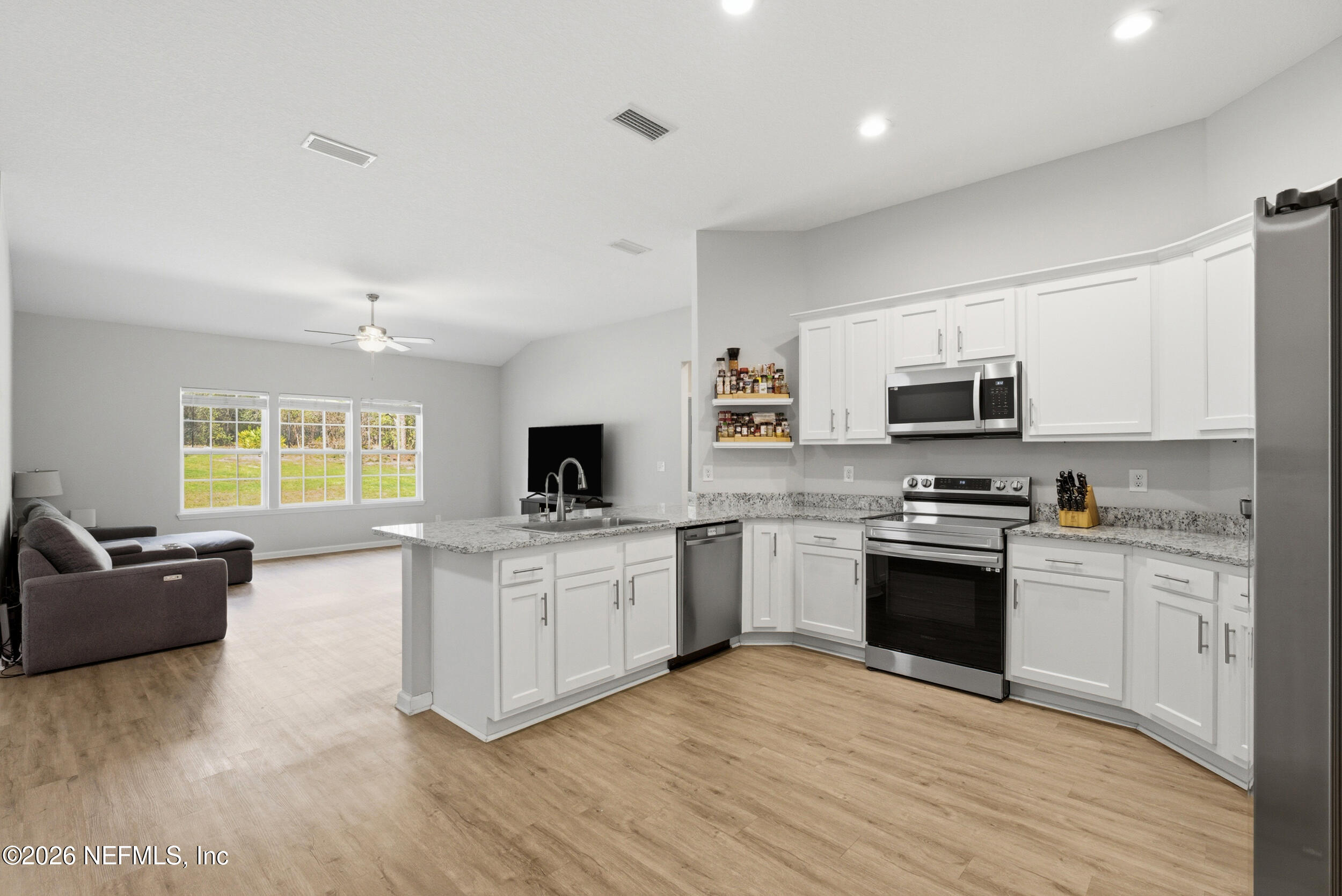 94 Sorrel Street Middleburg, FL 32068 - Photo 11 of 40 a kitchen with stainless steel appliances granite countertop a stove top oven a sink dishwasher a dining table and chairs with wooden floor