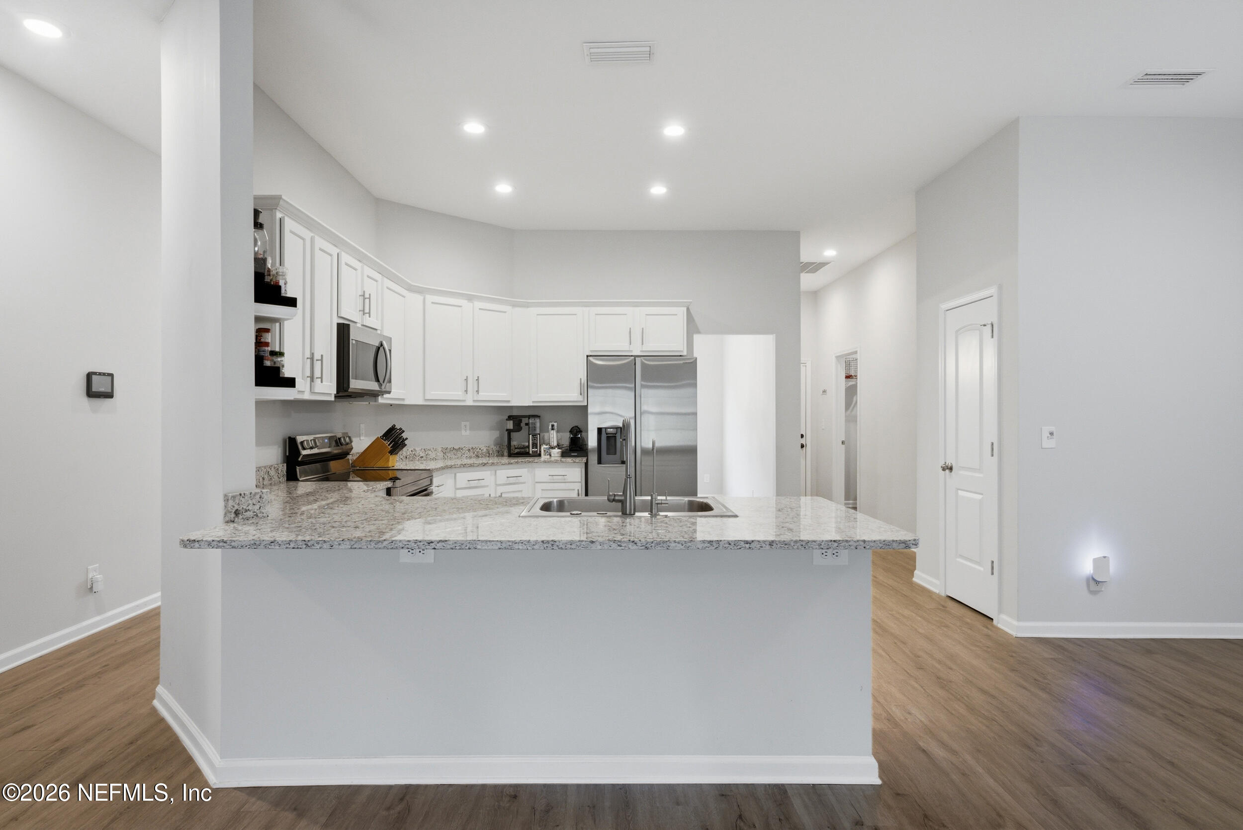 94 Sorrel Street Middleburg, FL 32068 - Photo 12 of 40 a large kitchen with stainless steel appliances granite countertop a stove a sink a refrigerator and white cabinets with wooden floor