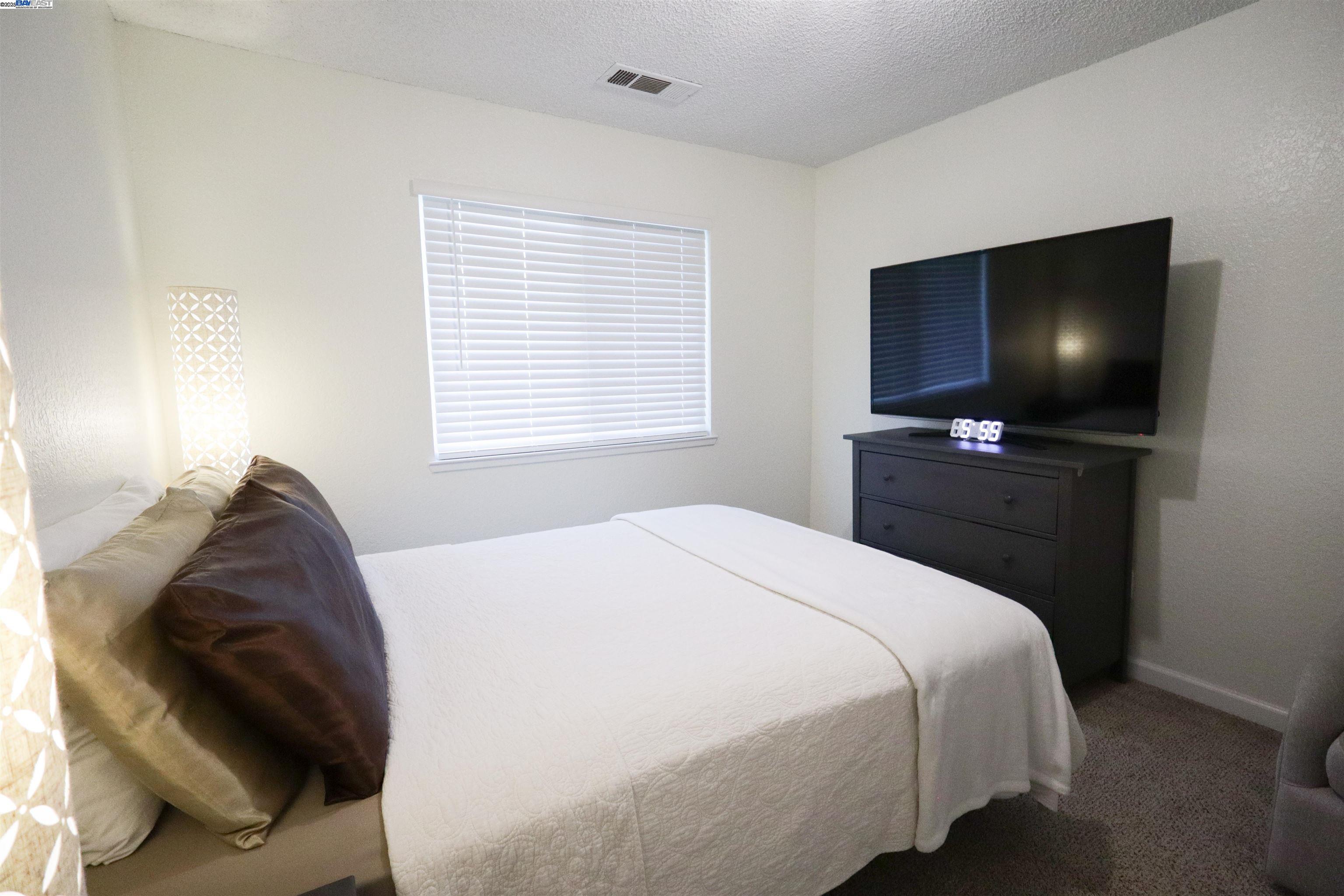 480 Cherry Lane, Unit E Manteca, CA 95337 - Photo 4 of 11 a bedroom with a bed and a flat screen tv