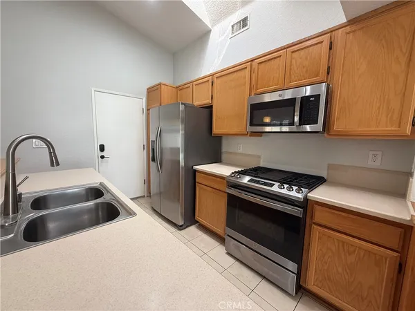 a kitchen with stainless steel appliances a sink a stove a microwave a refrigerator a sink and cabinets