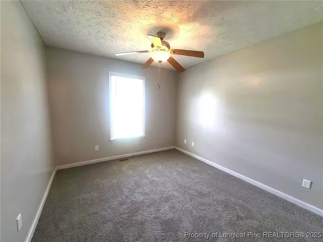 an empty room with a window and a fan