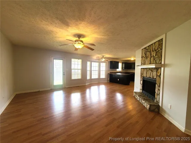 a view of empty room with fireplace and wooden floor