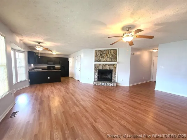 a view of empty room with a fireplace and wooden floor