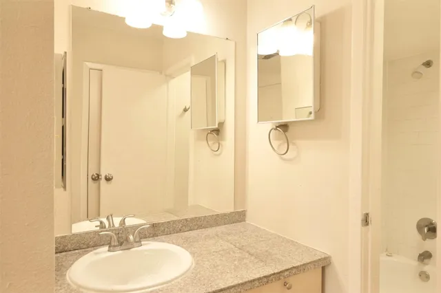a bathroom with a granite countertop sink a mirror and a shower