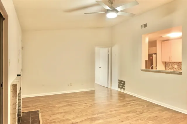 a view of an empty room with window and wooden floor