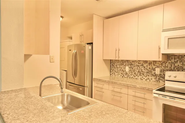 a kitchen with granite countertop a stove a sink and a refrigerator