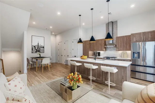 a kitchen with stainless steel appliances granite countertop a stove a sink a refrigerator and chairs