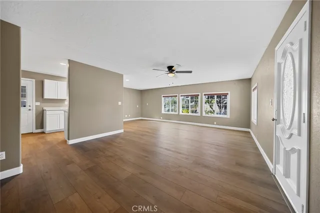 a view of an empty room with window and wooden floor